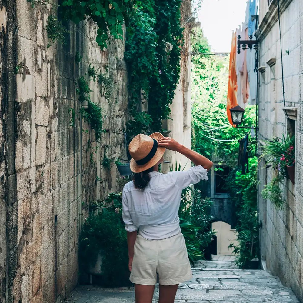 Girl tourist walking through ancient narrow streets on a beautiful summer day in Korcula, Croatia 