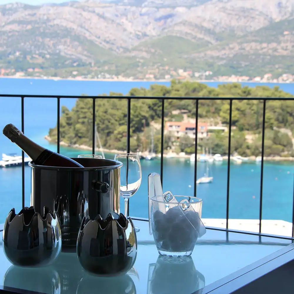 A chilled bottle of wine stands on the terrace table, overlooking the sea